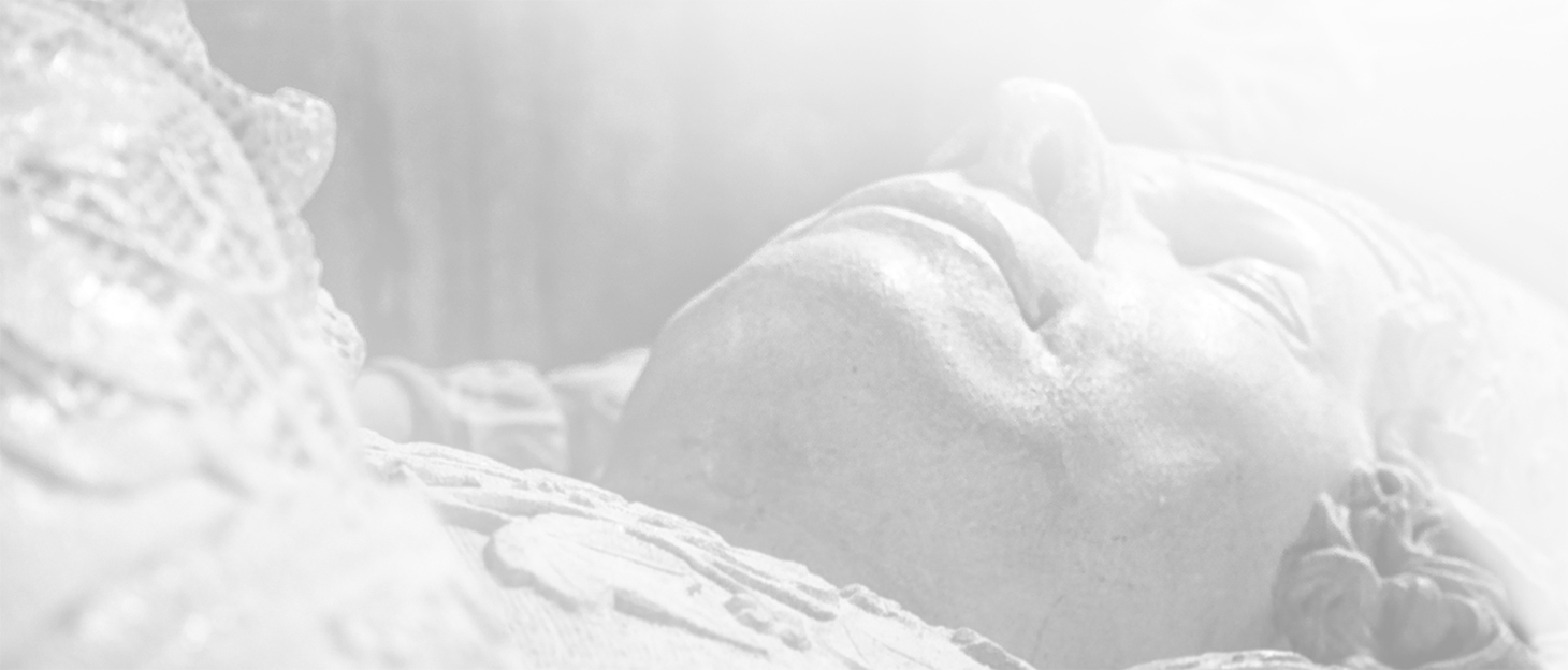 Close up Black and White photography of a sculpture of a dead man laying on a bed in a Cathedral